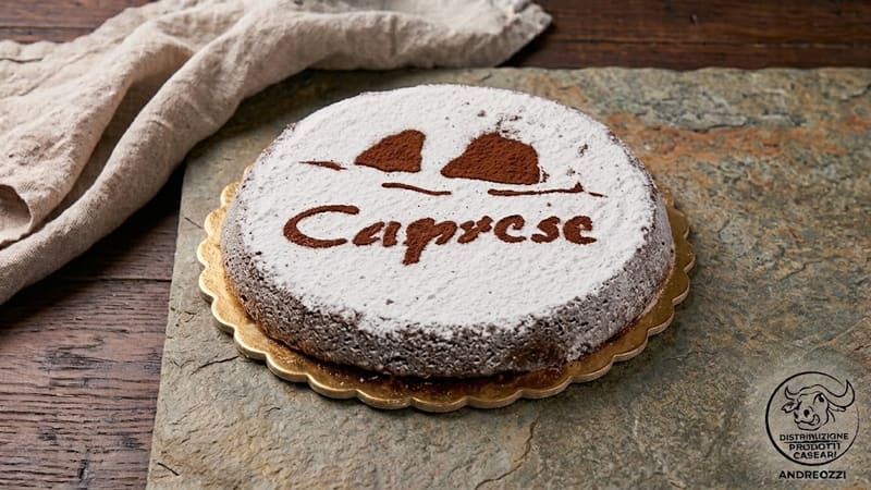 Una torta caprese intera con la scritta Caprese in zucchero a velo